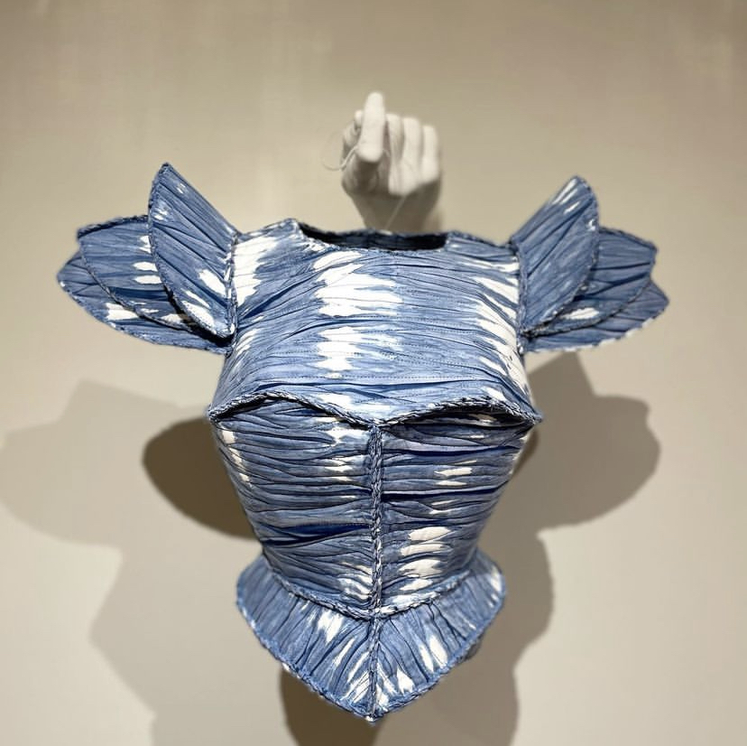 Susan Allred's armor-like fabric sculpture hung by the string on a hand mold